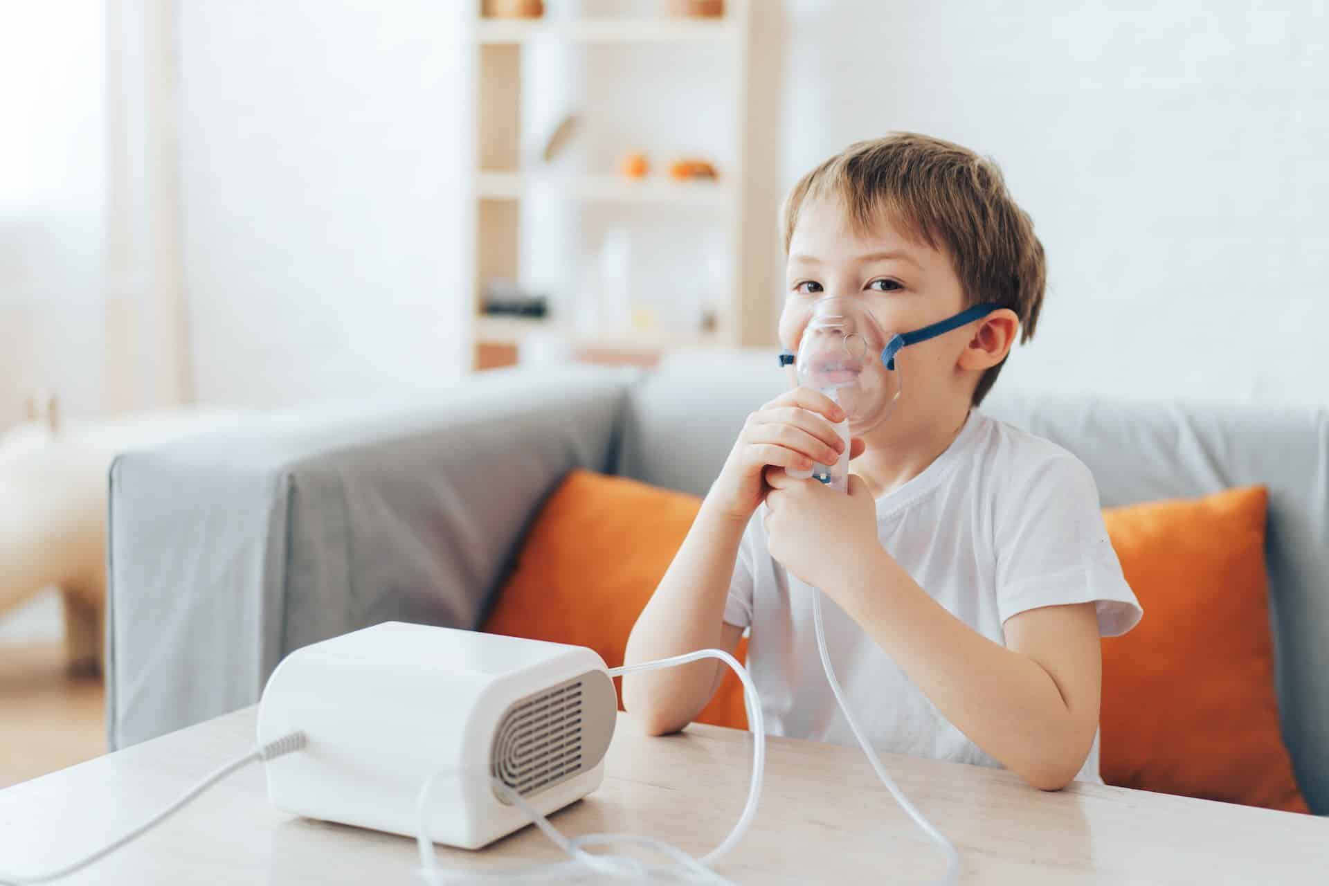 Niño con nebulizador en casa debido a humedad ambiental