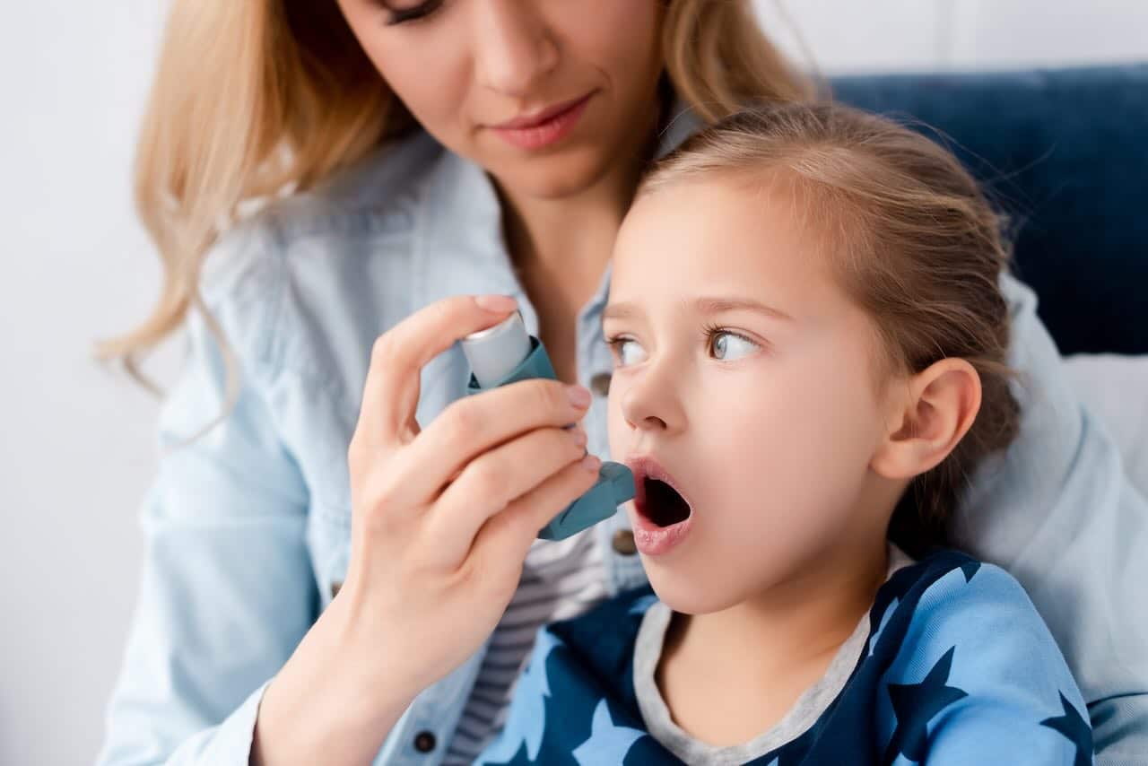 Niña utilizando inhalador por alergia causada por humedad