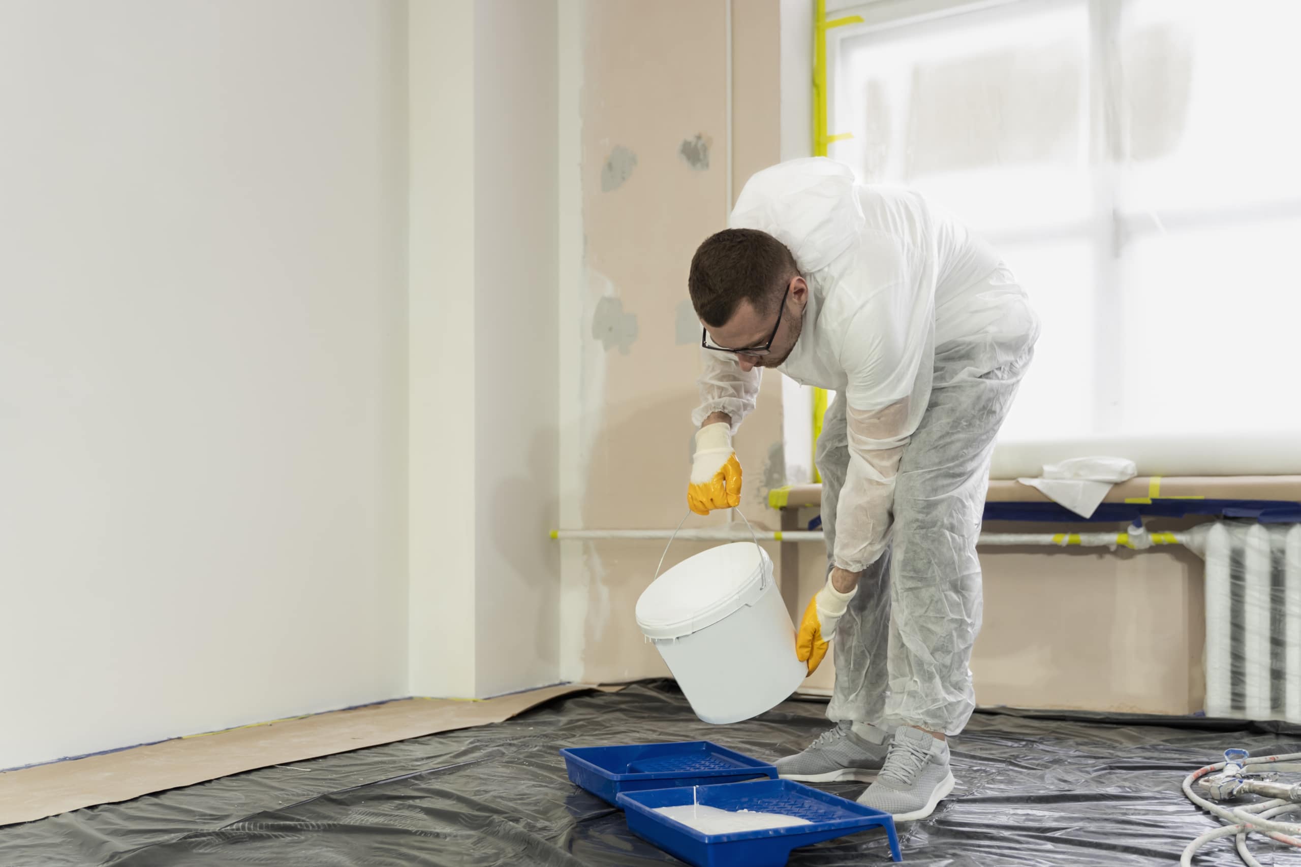 Técnico aplicando tratamiento antihumedad sobre pared blanca