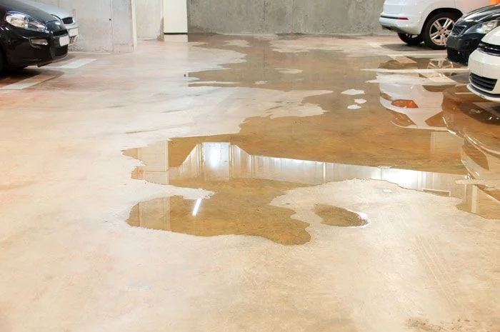 charco de agua en un garaje con coches